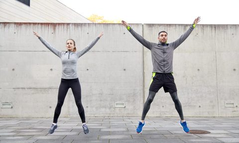 A man and a woman doing jumping jacks.