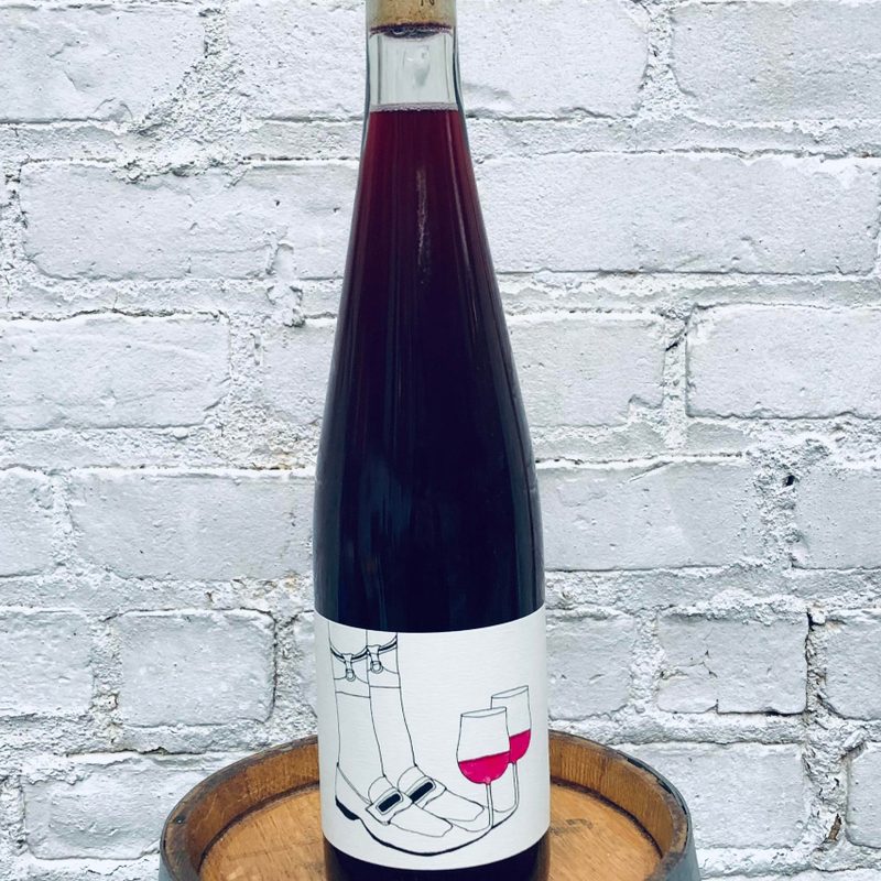 Bottle of Las Jaras | 'Slipper Sippers Nouveau,' Mendocino, California, United States 2021 against a wall.