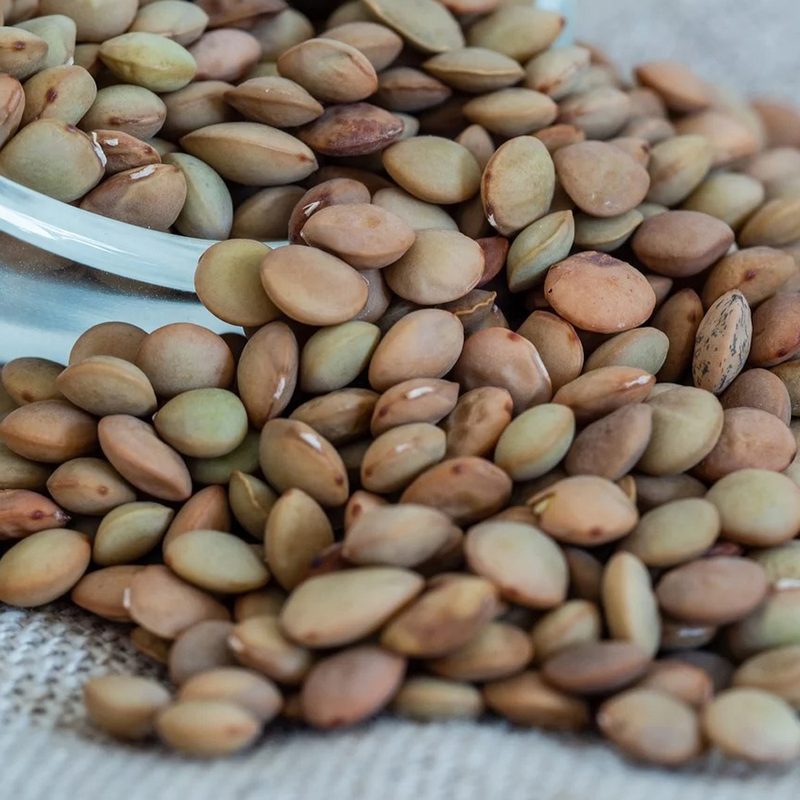 Lentils spilling from a transparent bowl.