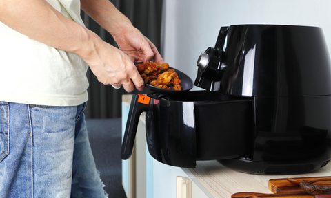 Putting fried chicken into the tray of an air fryer