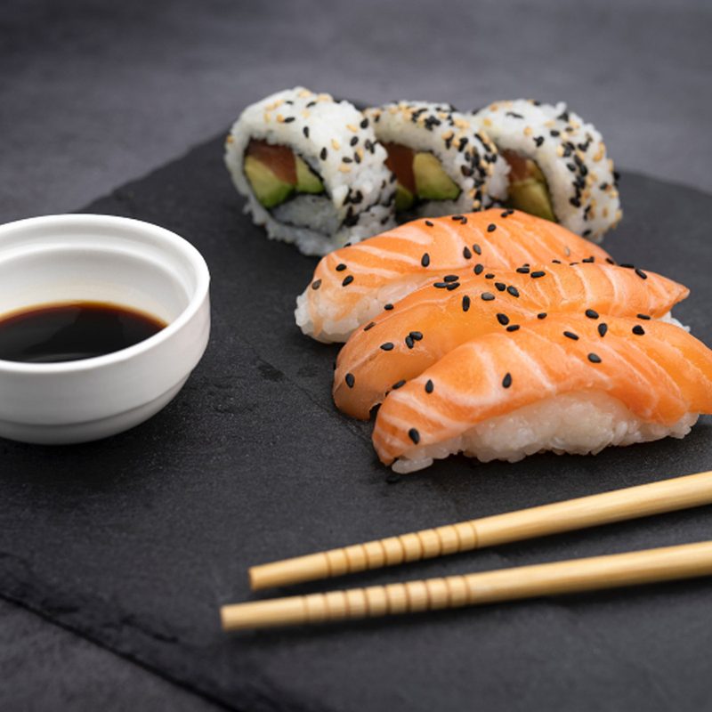 Sushi, soy sauce, and chopsticks on platter.