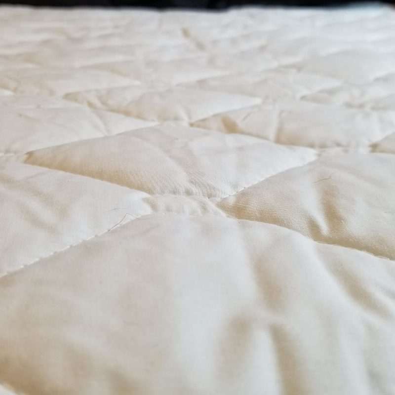 quilted mattress pad on a bed.
