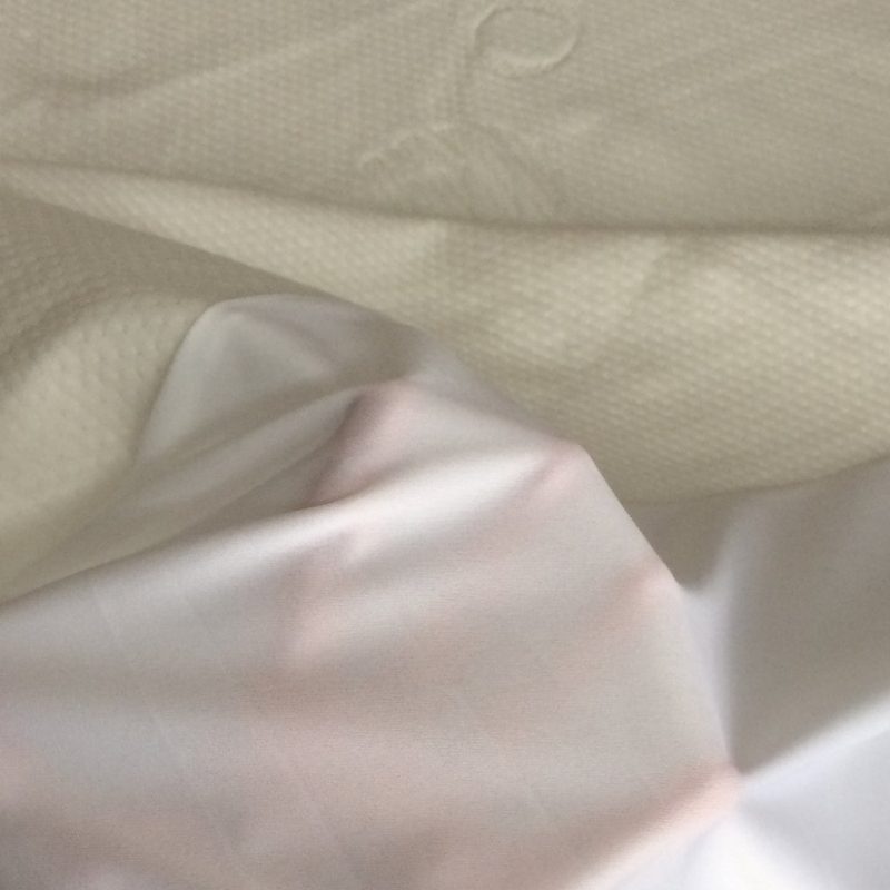 person's hand under a mattress protector.