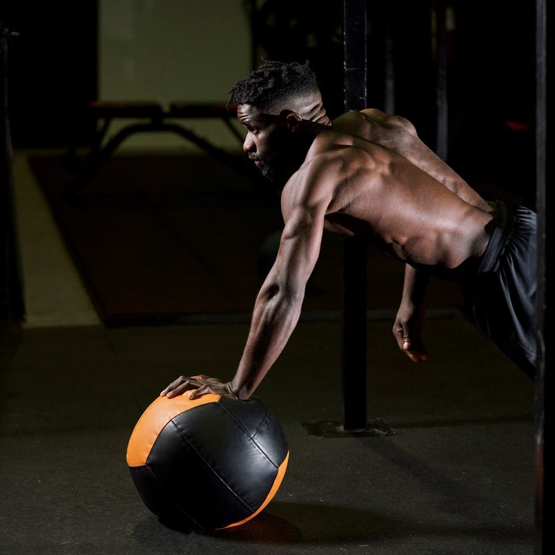 Black man exercising with a medicine ball at the gym.