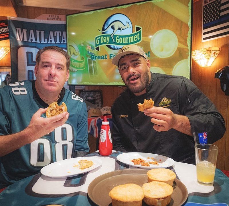 Michael Peacock with NFL player Jordan Mailatasharing a Aussie meat pie.