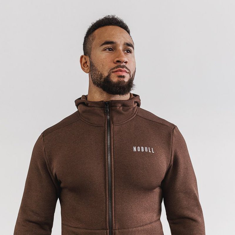 A midsection of a man wearing a brown Nobull Performance Zip-up Hoodie.