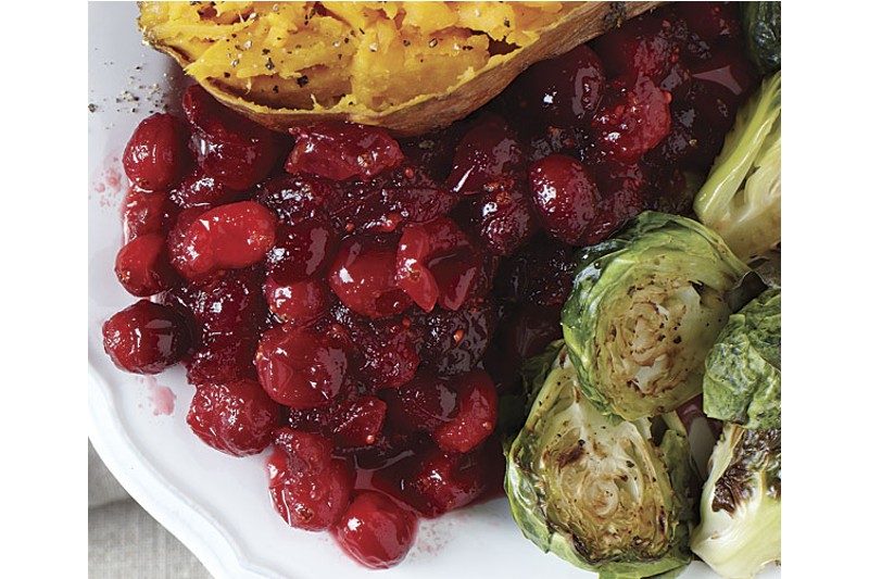 orange maple cranberry sauce on a plate next to brussles sprouts.
