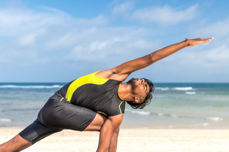 man doing yoga on the beach