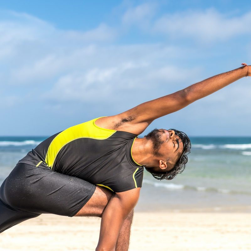 Man doing yoga on the beach.