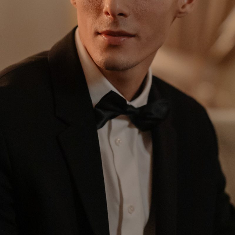 Upper portion of a man wearing a tuxedo, white shirt and black tie