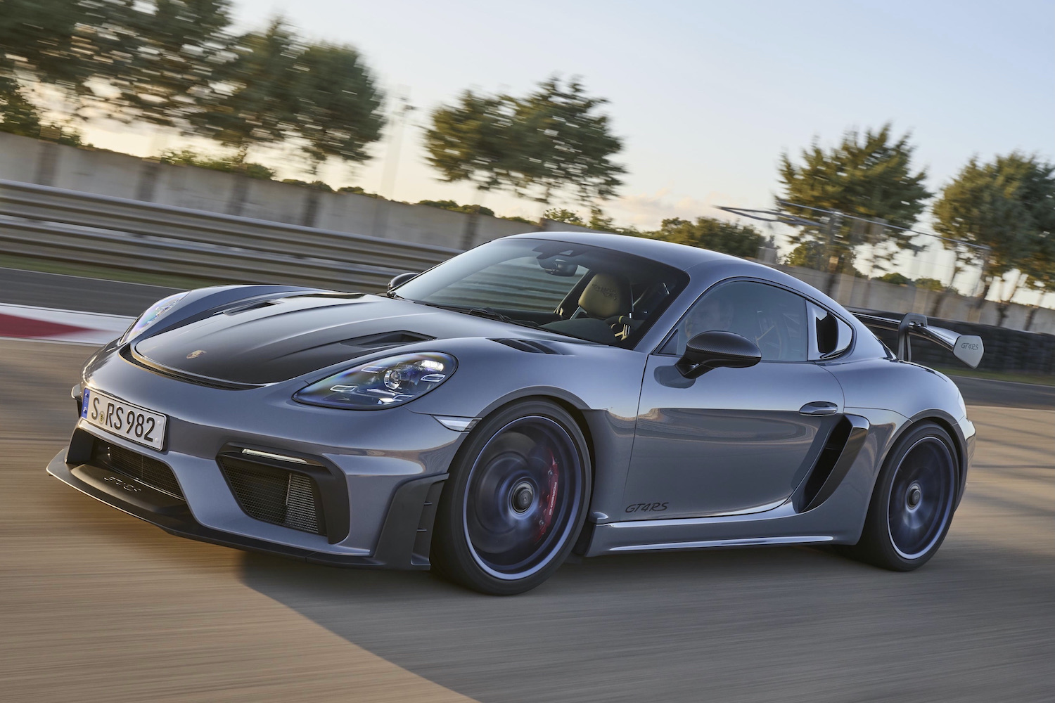 Porsche 718 Cayman GT4 RS driving fast on track from front end driver's side.