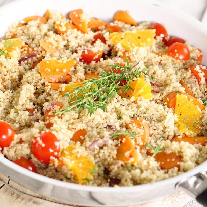 a Quinoa dish with tomatoes sitting on a wooden cutting board.
