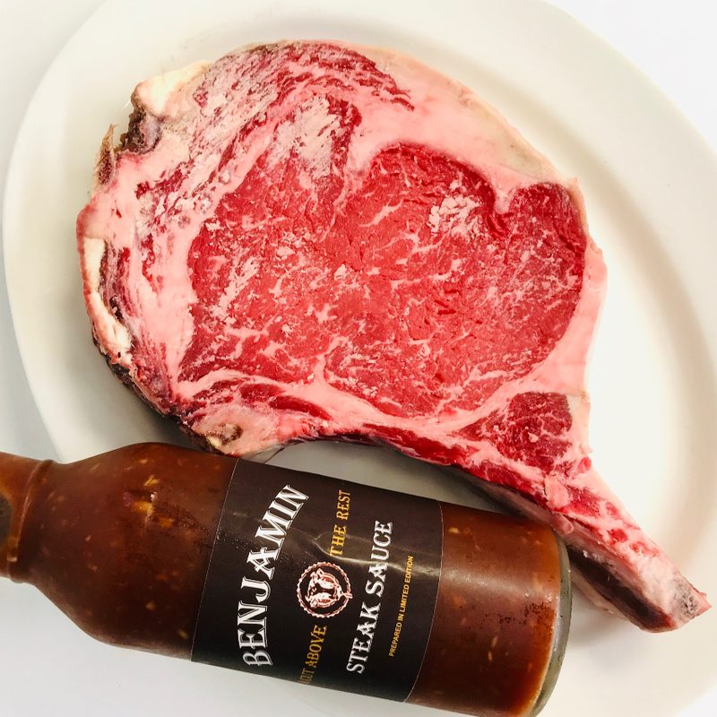 Raw ribeye with Benjamins Steak Sauce on a plate.