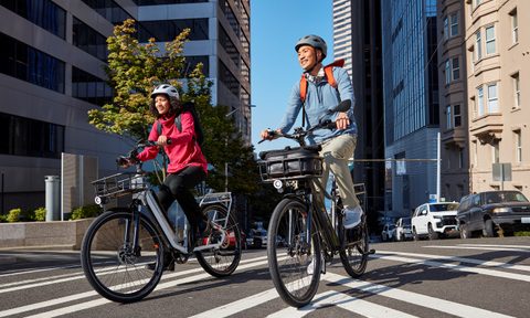 Riders on RadCity 5 Plus e-bike in a city street.