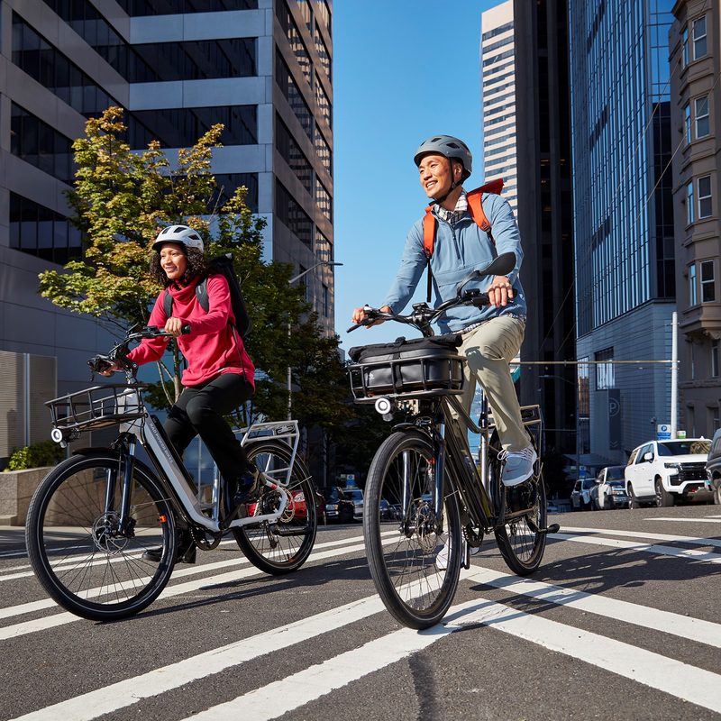 Riders on RadCity 5 Plus e-bike in a city street.