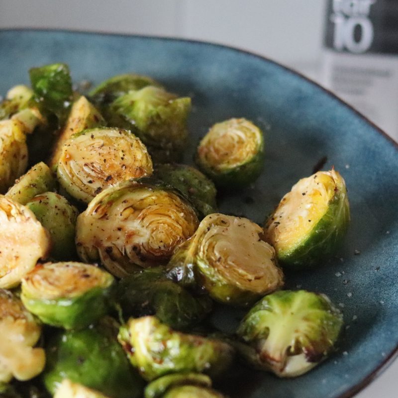 Blue bowl of roasted Brussels sprouts on a white kitchen counter