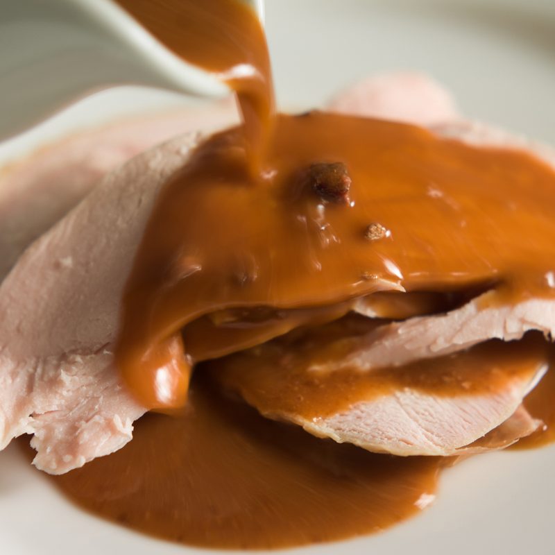 Giblet gravy being poured on turkey slices
