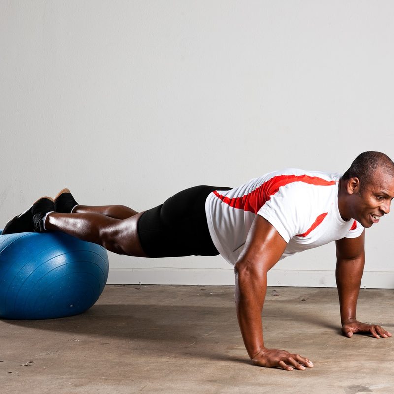 Man doing pushups with a stability ball.