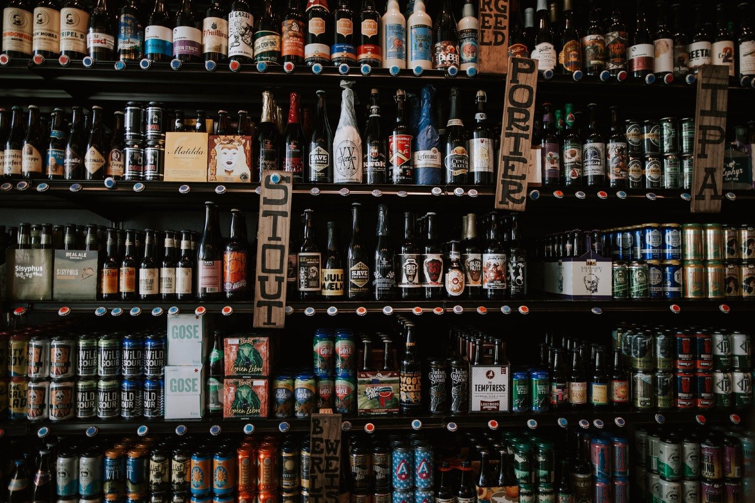 A shelf of stout beer next to porter and ipa.