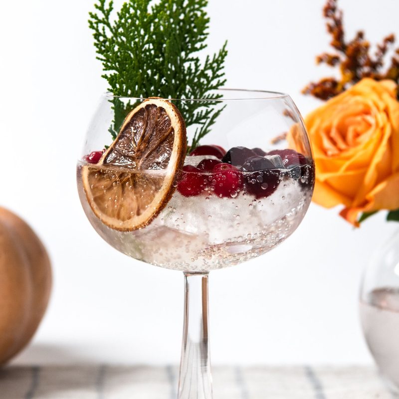 Thanksgiving Gin and Soda cocktail with pumpkin and roses in a glass bowl with water.