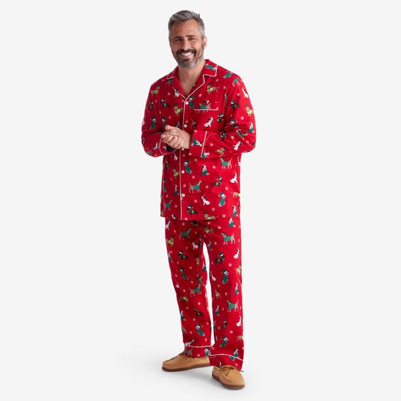 A male model wearing a red pajama set, featuring a print of dogs wearing Santa hats.
