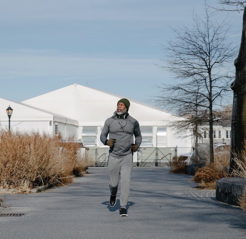 Man getting ready to run through the streets layered for colder weather.