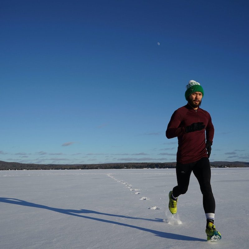 Man running through the snow in cold weather running gear.