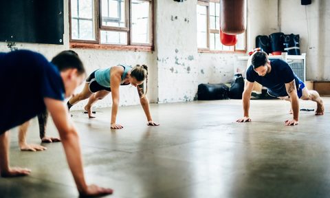 Group of friends doing push-ups at the gym.