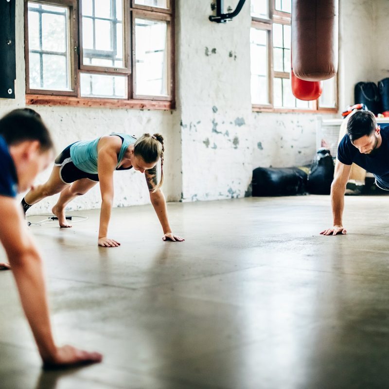 Group of friends doing push-ups at the gym.