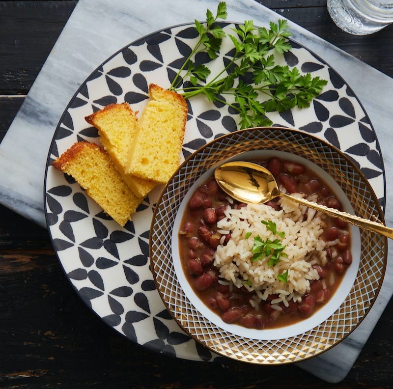 Bowl of Vegan Red Beans & Rice with Cornbread slices on a table.