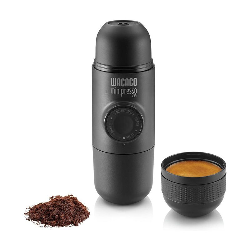 A Wacaco Minipresso beside a coffee powder and a cup of coffee.