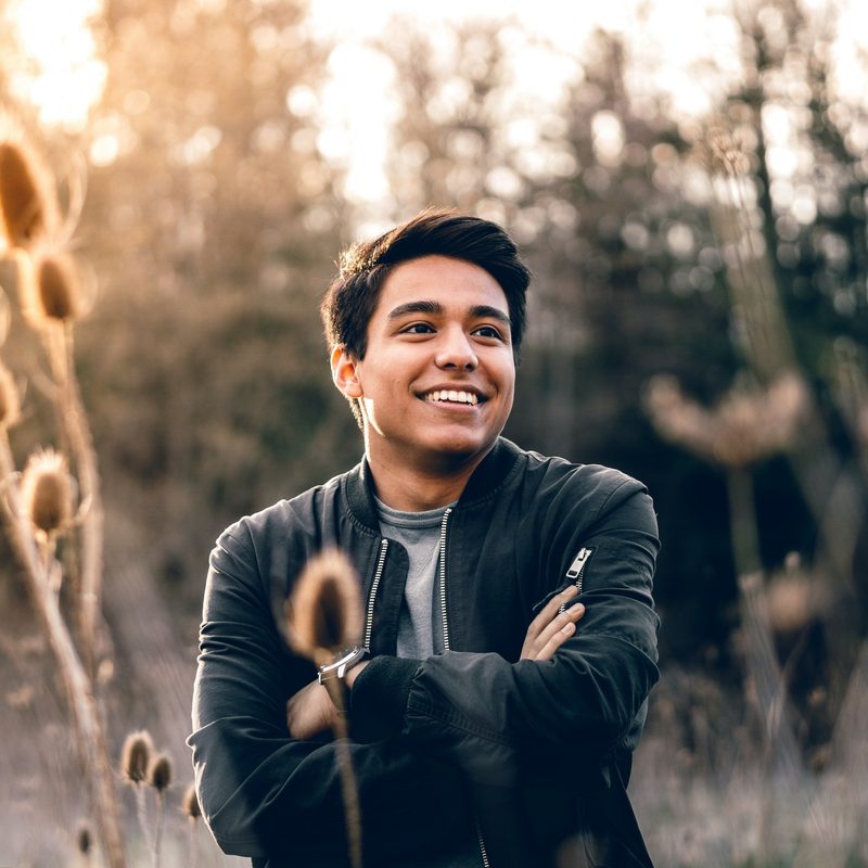 Man smiling in a field outside.