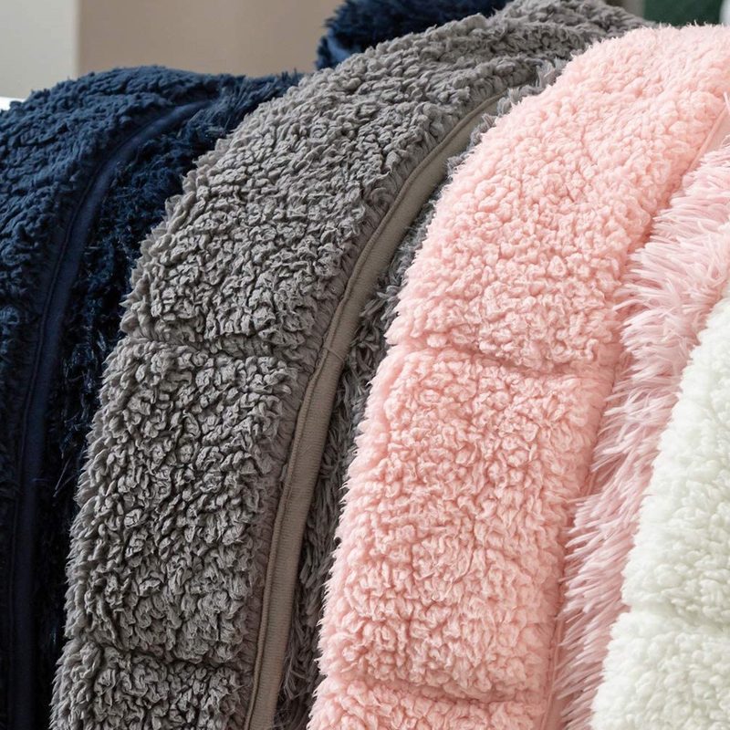 Four Wemore Shaggy Long Fur Faux Fur Weighted Blankets in various colors on a bedsheet.