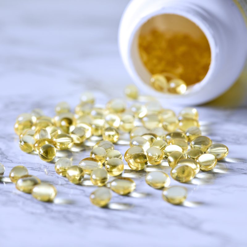 A bottle and vitamin D capsules scattered on a table.