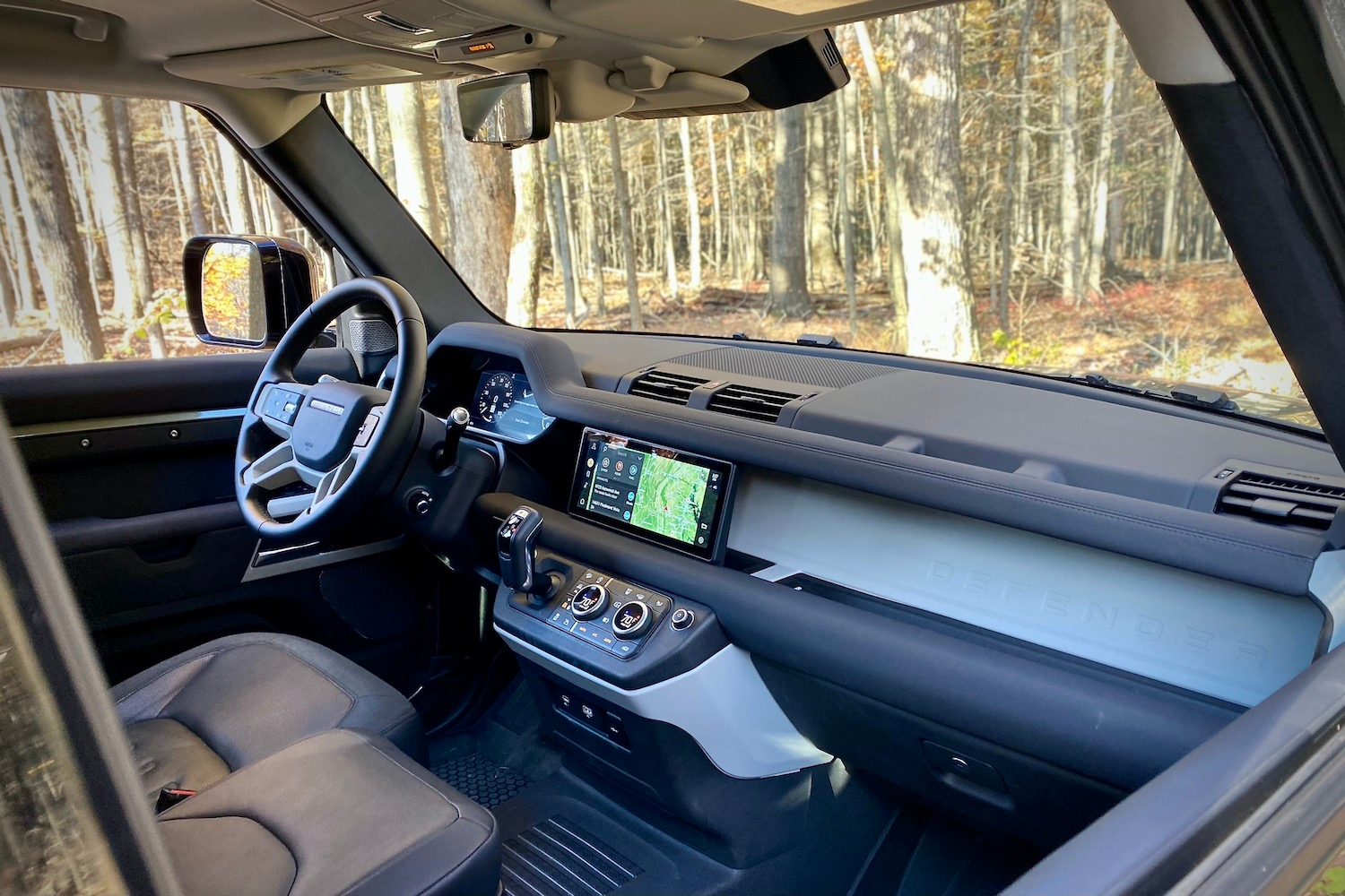 Land Rover Defender dashboard from passenger's side with trees in the background.
