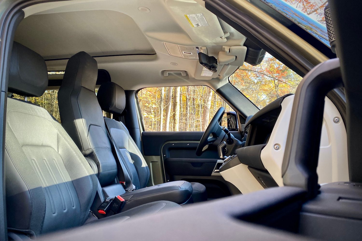 Front seats and door handle in Land Rover Defender from passenger's side.