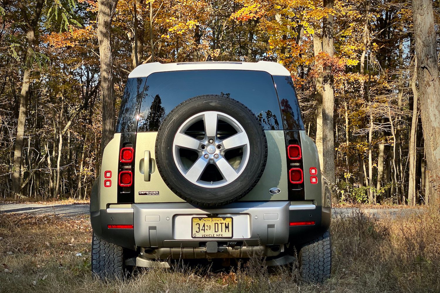 Close up of Land Rover Defender with trees in the back.