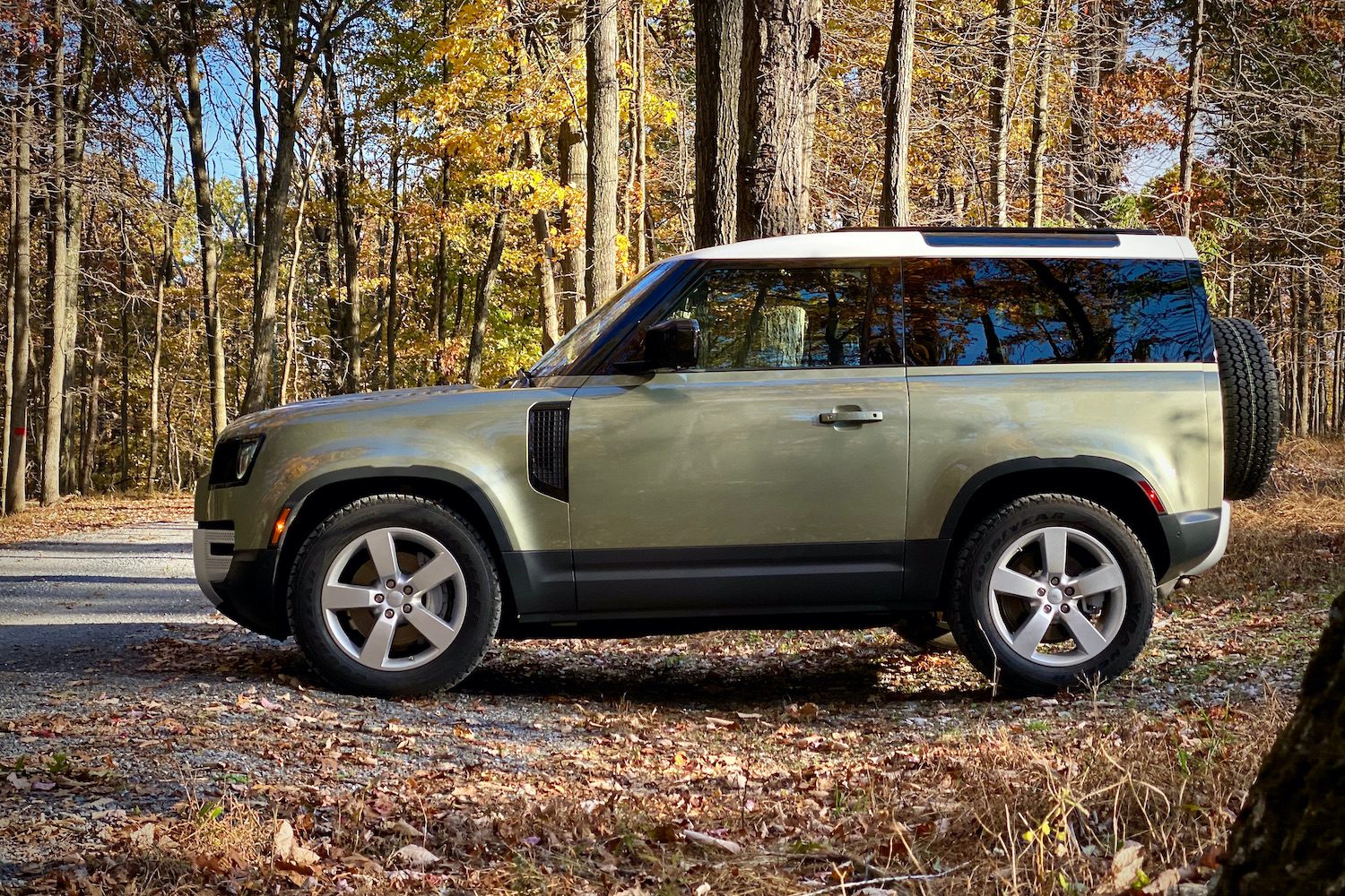 Land Rover Defender silouhette from the side in front of trees.