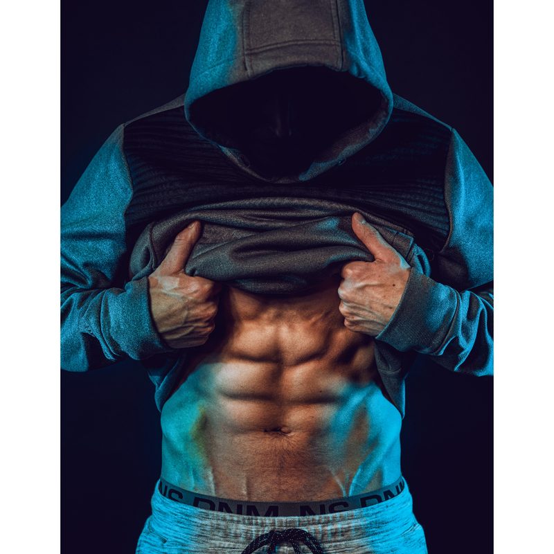 Hooded man displaying six-pack abs.