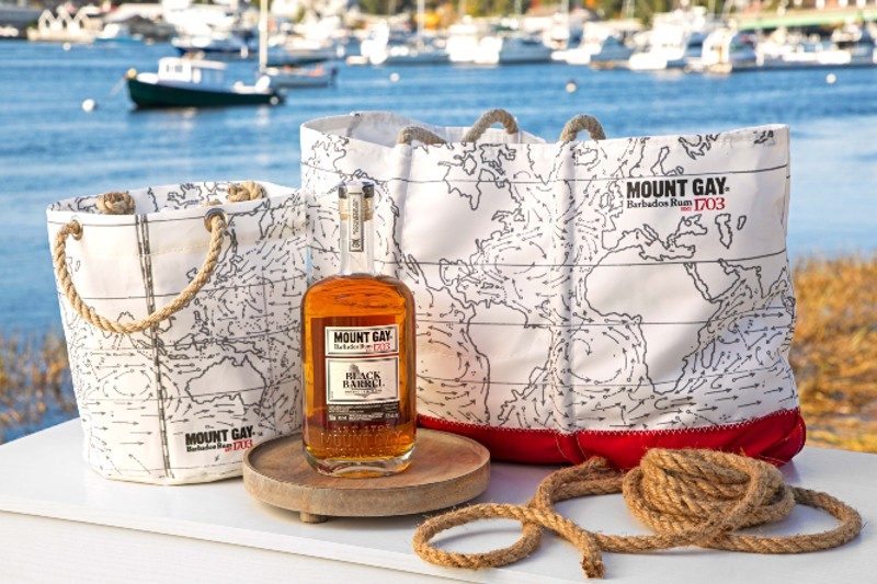 bottle of mount gay rum sitting next to mount gay tote bags.