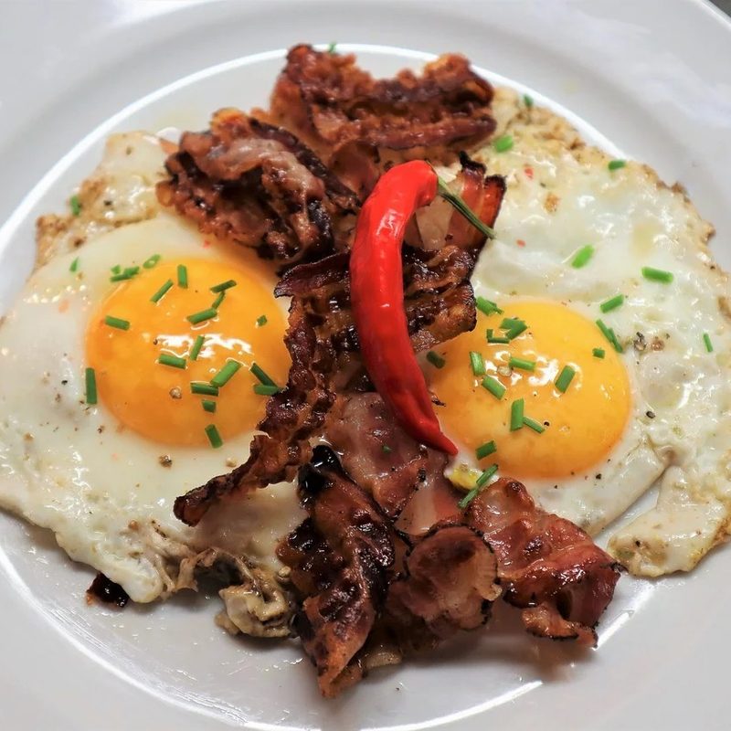 Bacon and eggs on a white plate.