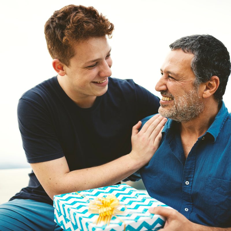 A father happily holding the gift his son gave in the outdoors.