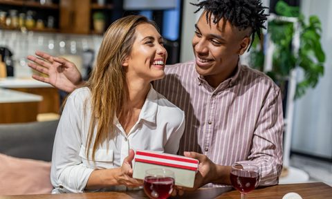 A husband surprising his wife with a gift at home.