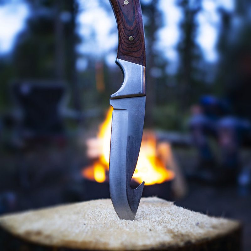 Closeup of hunting fishing camping knife blade In campfire log In outdoor scene