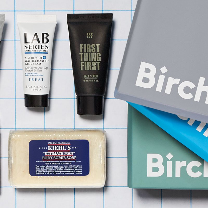 Assorted skincare products beside three Birchbox Men boxes.