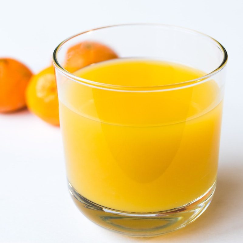 Glass of orange juice with oranges in the background