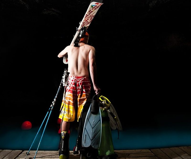 Shirtless man carrying diving equipment.