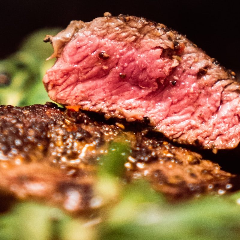 medium rare sliced steak on a bed of greens.