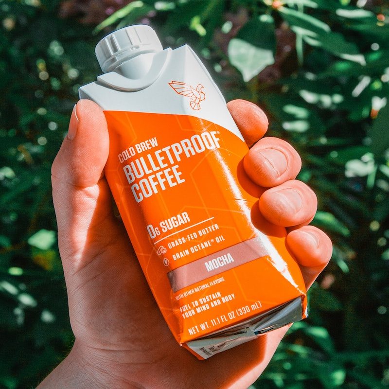 Hand holding creamy bulletproof coffee