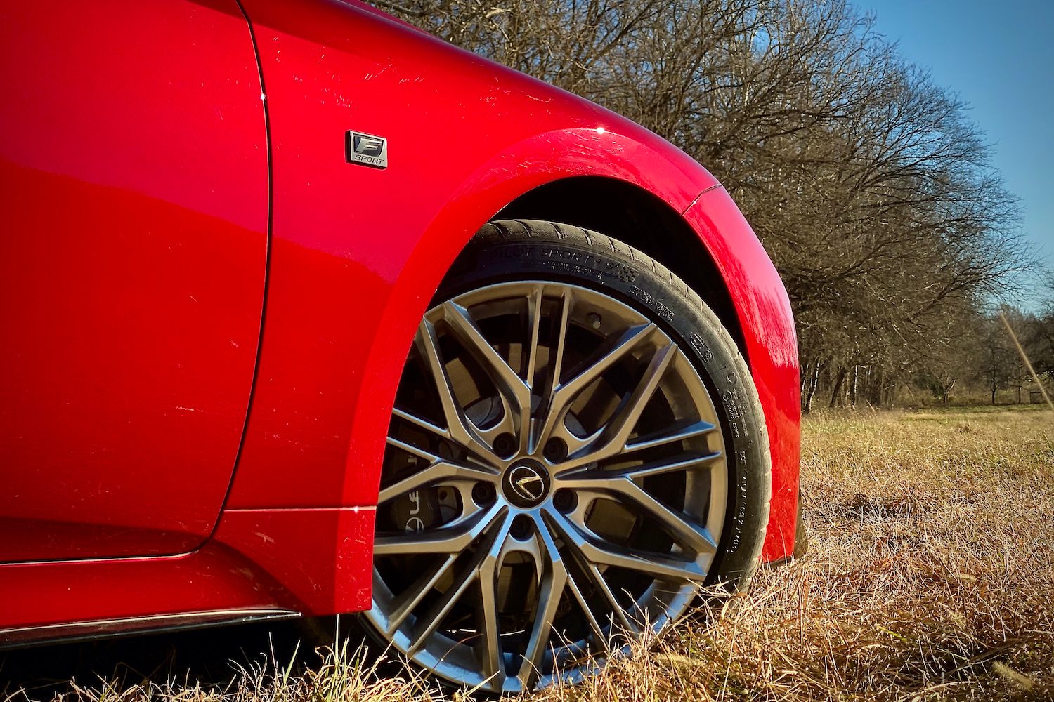 Close up of Lexus IS 500 front passenger's side wheel in a grassy field.